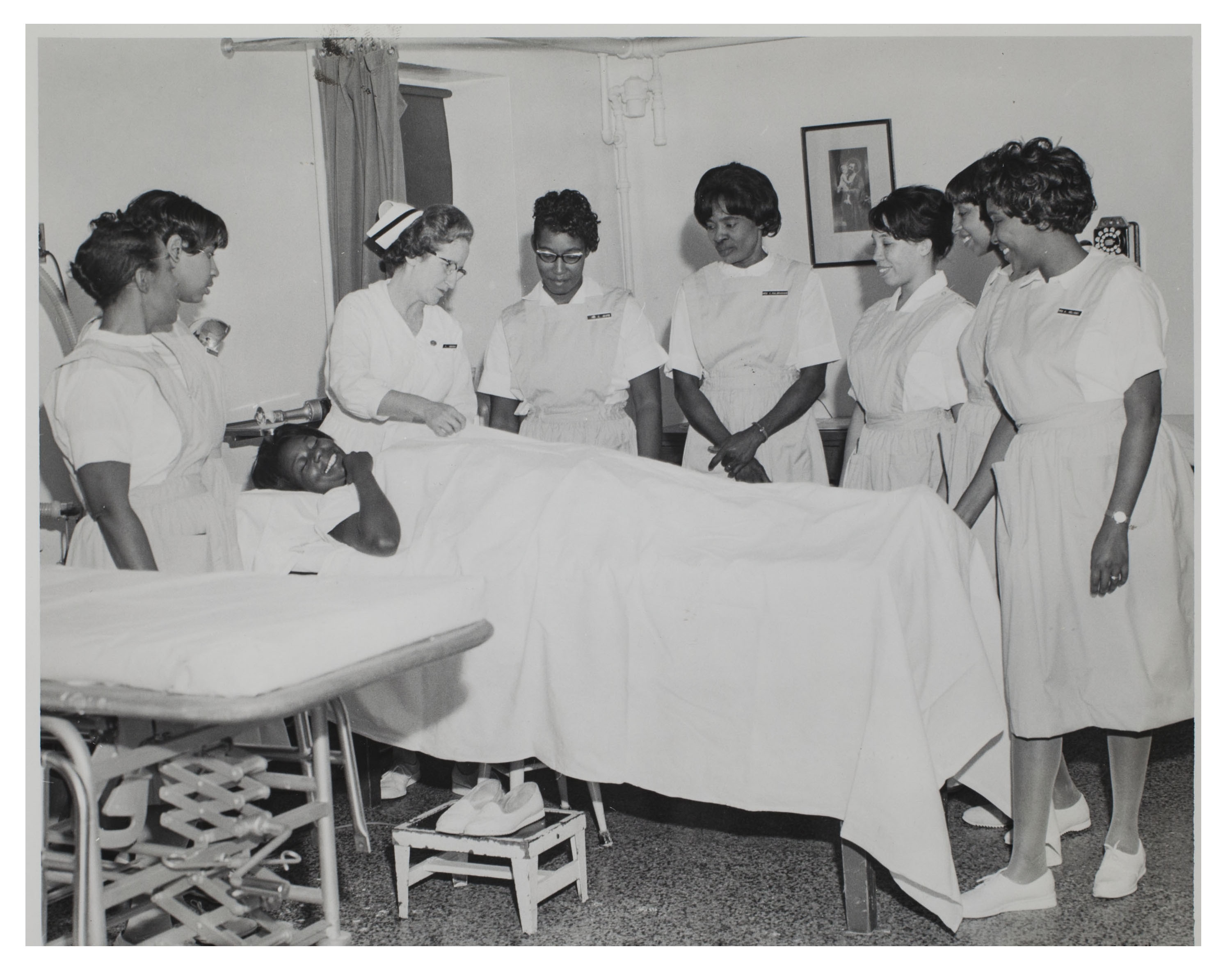 A black female in a hospital bed surrounded by 8 nurses and doctors.